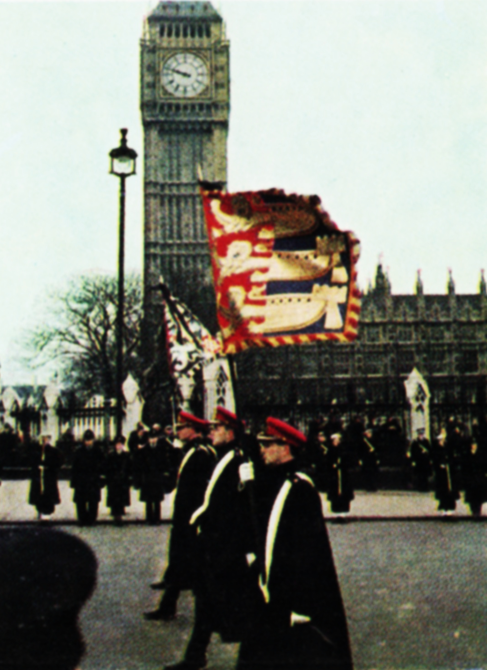 Heralds bearing a banner march past the Palace of Westminster